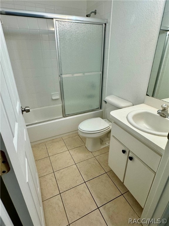 full bathroom with combined bath / shower with glass door, vanity, tile patterned floors, and toilet