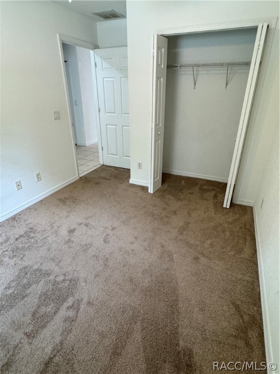 unfurnished bedroom with carpet flooring and a closet