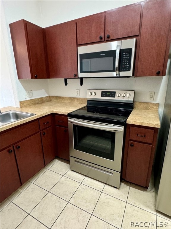 kitchen with light tile patterned flooring, sink, and stainless steel appliances