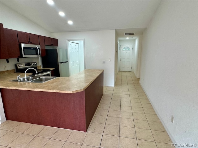 kitchen featuring sink, stainless steel appliances, kitchen peninsula, vaulted ceiling, and light tile patterned floors