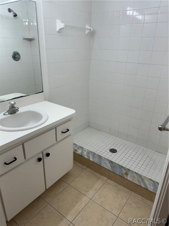 bathroom with tile patterned floors, vanity, and a tile shower