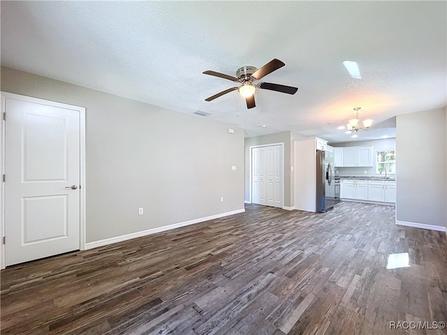 unfurnished living room featuring ceiling fan with notable chandelier, sink, a textured ceiling, and dark hardwood / wood-style floors