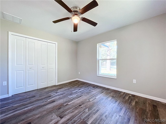 unfurnished bedroom featuring a textured ceiling, ceiling fan, a closet, and dark hardwood / wood-style floors