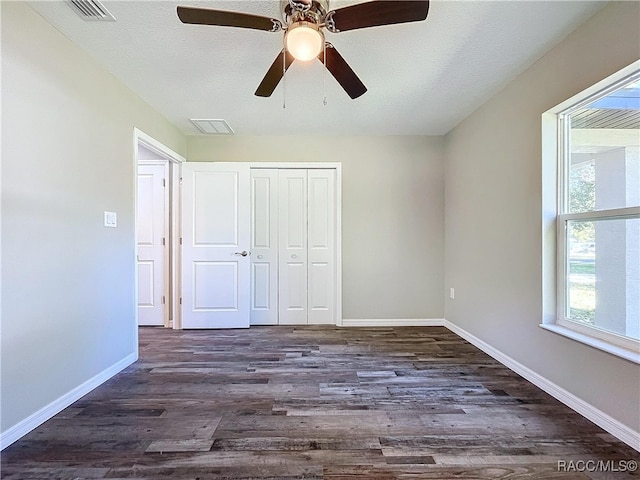 unfurnished bedroom featuring dark wood-type flooring, ceiling fan, and a closet