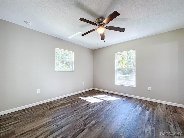 empty room featuring a textured ceiling, ceiling fan, a wealth of natural light, and dark hardwood / wood-style floors