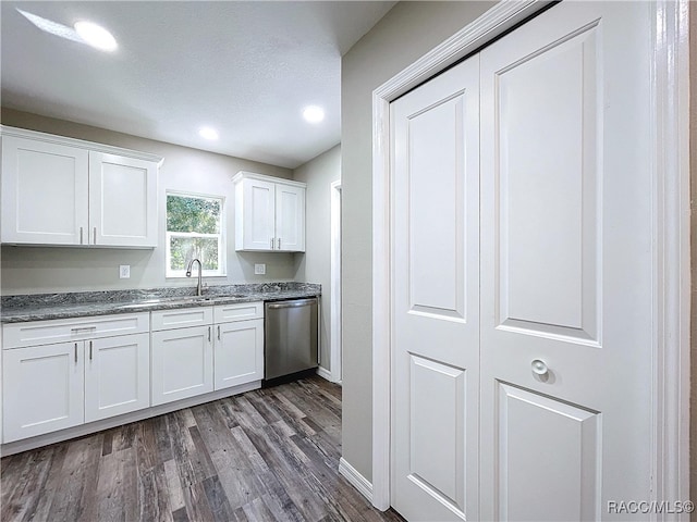 kitchen featuring dark wood-type flooring, stainless steel dishwasher, white cabinets, and sink