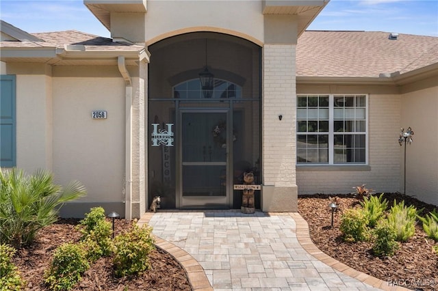 2056 W Learwood Pl, Beverly Hills, FL 34465 - view of exterior entry featuring brick siding, stucco siding, and a shingled roof