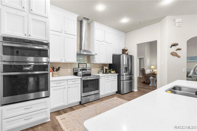 2056 W Learwood Pl, Beverly Hills, FL 34465 - kitchen featuring stainless steel appliances, wall chimney range hood, a sink, light countertops, and light wood-style floors