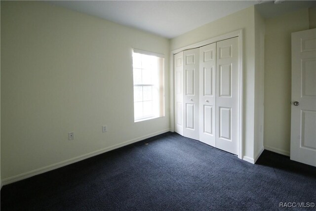4450 E Windmill Dr Unit 106, 107, 206, 207, Inverness, FL 34453 - unfurnished bedroom with dark carpet, baseboards, and a closet
