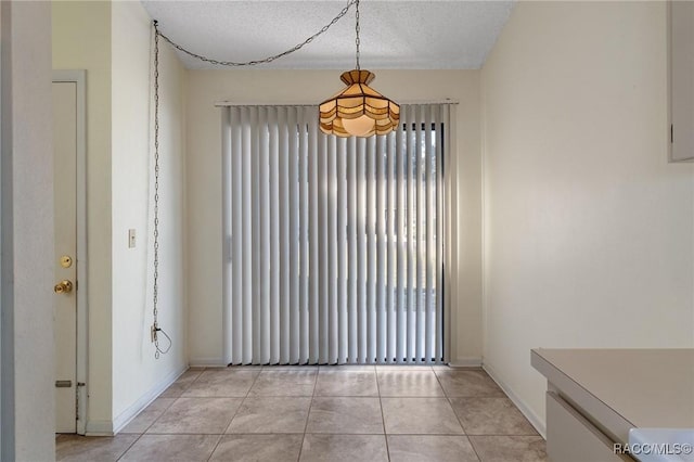 unfurnished dining area featuring light tile patterned floors and a textured ceiling