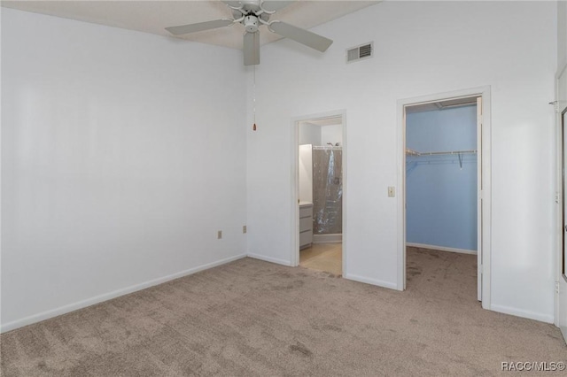 unfurnished bedroom with light carpet, a walk in closet, ensuite bathroom, ceiling fan, and a closet