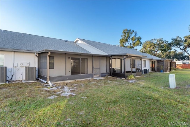 rear view of property featuring a sunroom, central air condition unit, and a lawn