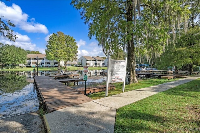 view of property's community with a lawn, a water view, and a boat dock