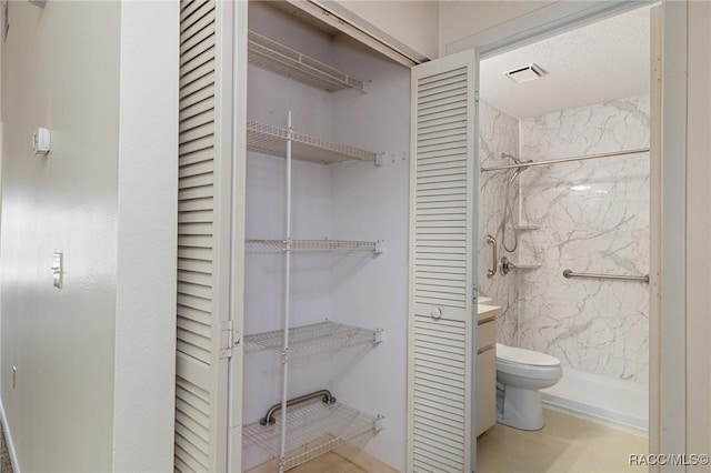 bathroom with vanity, toilet, and a tile shower