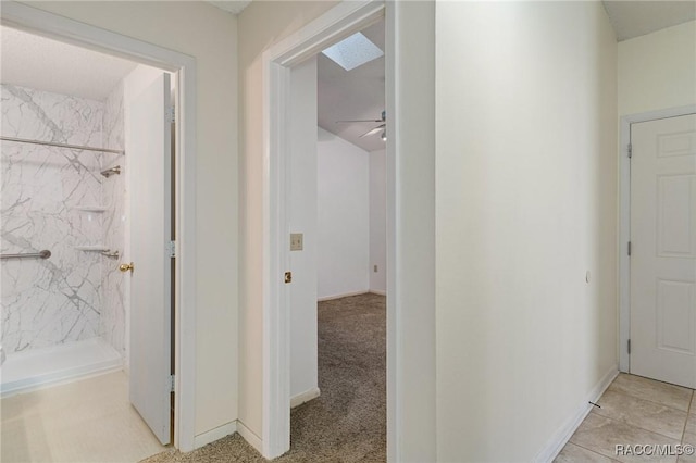 corridor with a skylight and light colored carpet