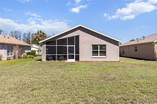 rear view of house with a sunroom, a yard, and stucco siding