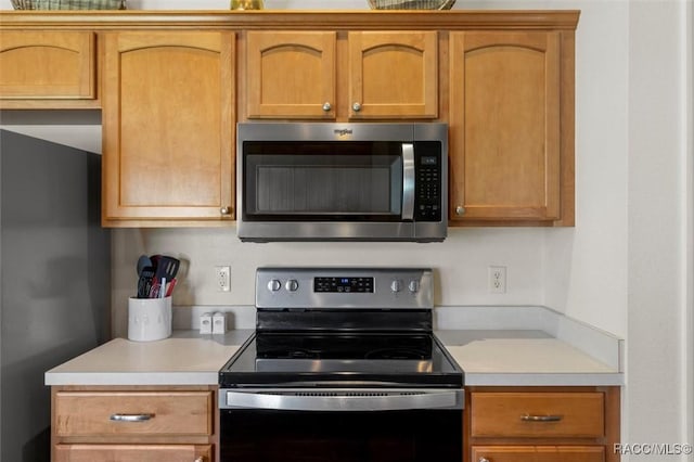 kitchen featuring light countertops, stainless steel microwave, and black electric range oven