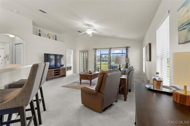 living area with arched walkways, light colored carpet, visible vents, a ceiling fan, and vaulted ceiling