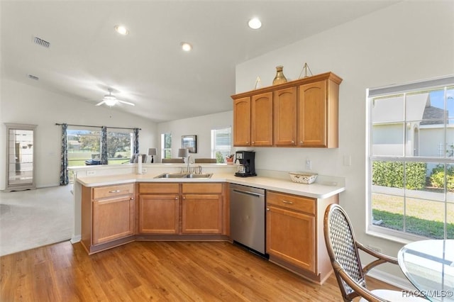 kitchen with lofted ceiling, visible vents, a sink, dishwasher, and a peninsula