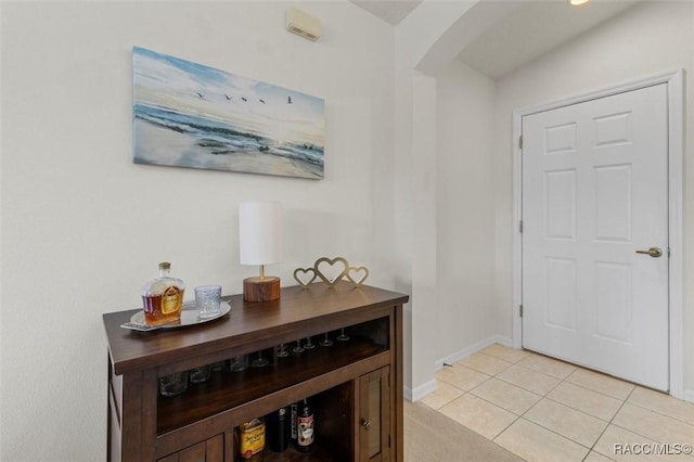 foyer entrance featuring light tile patterned floors, arched walkways, and baseboards