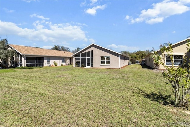 rear view of house featuring a lawn and a sunroom