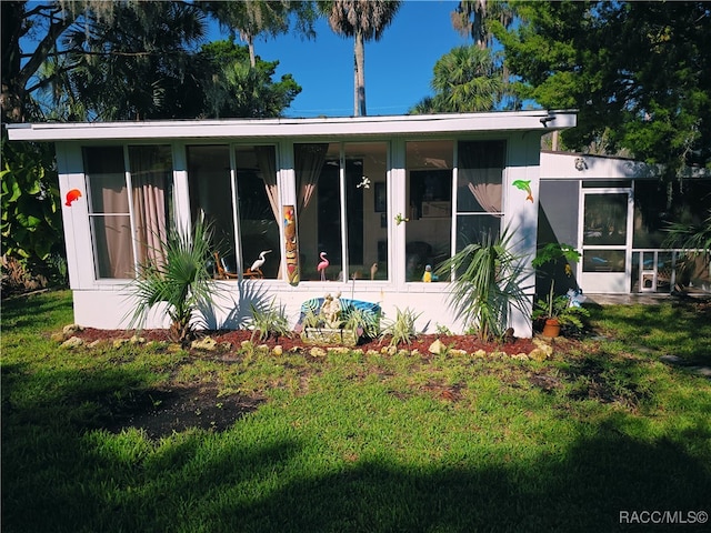 back of property with a yard and a sunroom