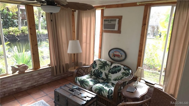 sitting room featuring a wall mounted air conditioner, light tile patterned floors, and ceiling fan