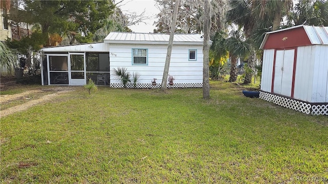 back of property with a sunroom, a storage shed, and a lawn