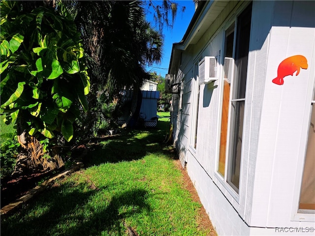 view of side of property with a lawn and a wall mounted AC