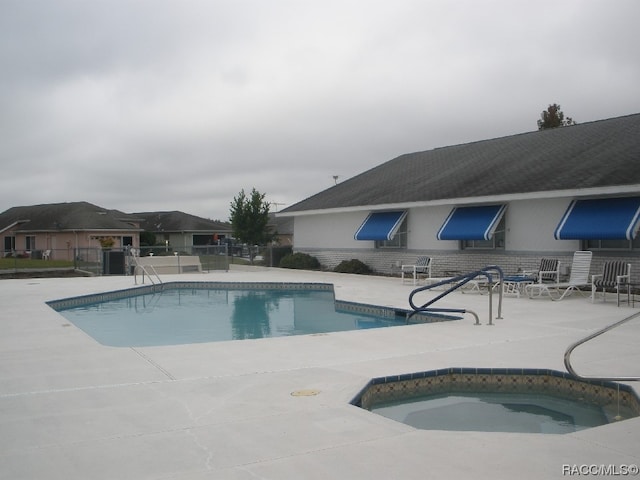 view of swimming pool featuring a patio and a hot tub