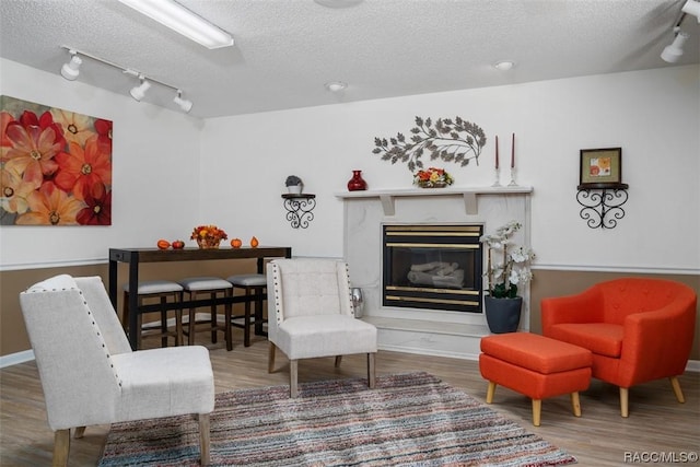 10522 S Drew Bryant Cir, Floral City, FL 34436 - living area featuring a textured ceiling, wood finished floors, a glass covered fireplace, rail lighting, and baseboards