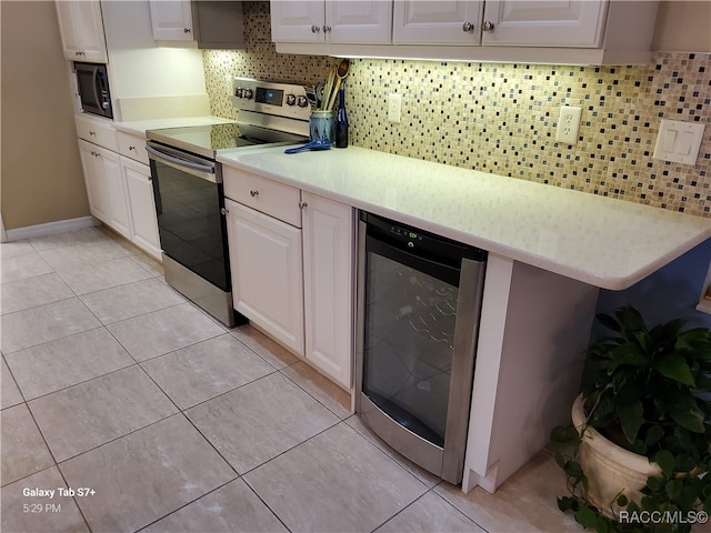 kitchen featuring backsplash, beverage cooler, electric stove, white cabinetry, and light tile patterned flooring