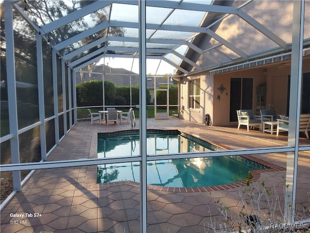 view of swimming pool with glass enclosure and a patio