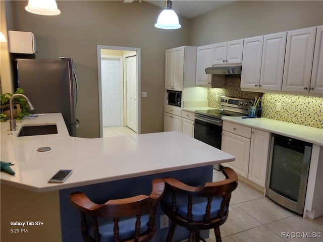 kitchen featuring appliances with stainless steel finishes, a kitchen breakfast bar, white cabinets, wine cooler, and hanging light fixtures