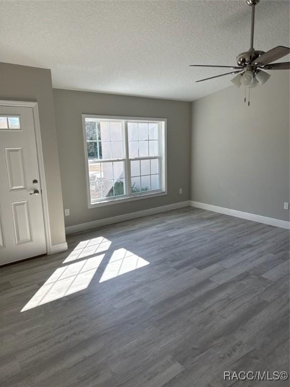 interior space featuring a ceiling fan, a textured ceiling, baseboards, and wood finished floors