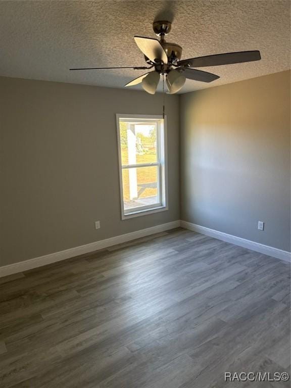 spare room featuring dark wood-style floors, ceiling fan, a textured ceiling, and baseboards