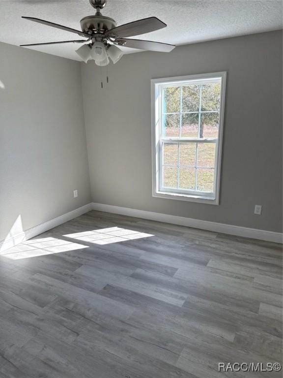 spare room featuring baseboards, a textured ceiling, and wood finished floors