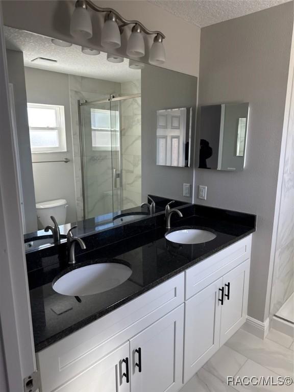 full bath featuring a textured ceiling, a stall shower, and a sink