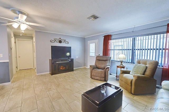 living room with crown molding, a fireplace, ceiling fan, and a textured ceiling