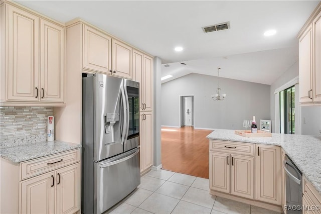 8831 E Sandpiper Dr, Inverness, FL 34450 - kitchen with cream cabinets, stainless steel appliances, a chandelier, lofted ceiling, and decorative backsplash