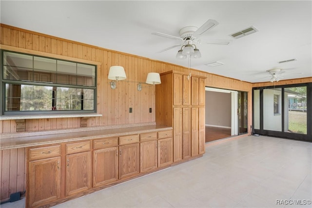 8831 E Sandpiper Dr, Inverness, FL 34450 - kitchen featuring wooden walls, a ceiling fan, light countertops, and brown cabinetry