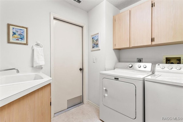 laundry room with cabinets, sink, a textured ceiling, separate washer and dryer, and light tile patterned flooring