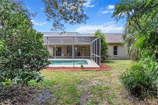 back of property featuring a patio, glass enclosure, and a lawn