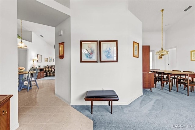 hall with a notable chandelier, high vaulted ceiling, and light tile patterned flooring