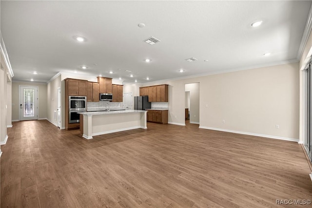 5235 N Sonora Ter, Beverly Hills, FL 34465 - kitchen featuring stainless steel appliances, open floor plan, crown molding, an island with sink, and brown cabinets