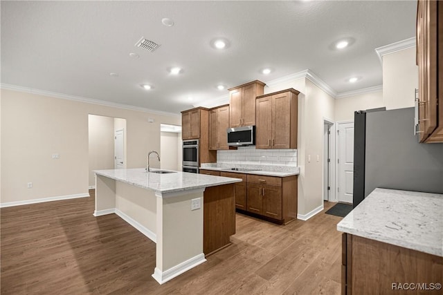 5235 N Sonora Ter, Beverly Hills, FL 34465 - kitchen featuring appliances with stainless steel finishes, ornamental molding, tasteful backsplash, a center island with sink, and wood finished floors