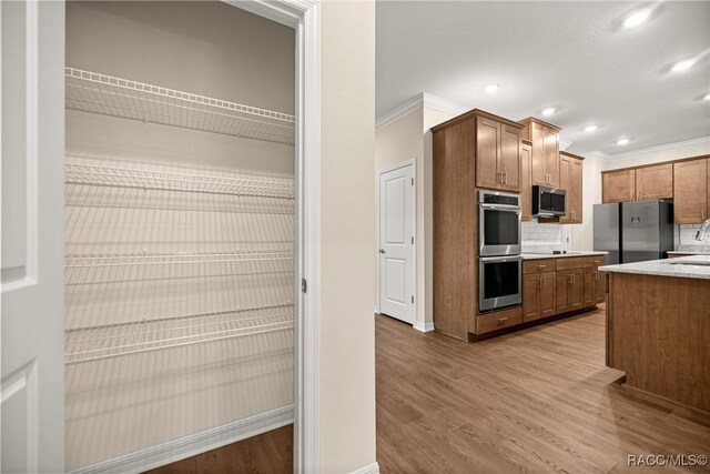 5235 N Sonora Ter, Beverly Hills, FL 34465 - kitchen with appliances with stainless steel finishes, backsplash, crown molding, light wood finished floors, and light countertops