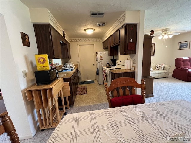 kitchen with white appliances, sink, ceiling fan, a textured ceiling, and dark brown cabinetry