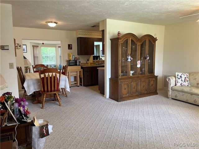 dining space with light carpet and a textured ceiling