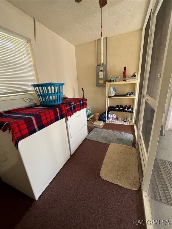 interior space with a textured ceiling, electric panel, dark carpet, and washing machine and clothes dryer